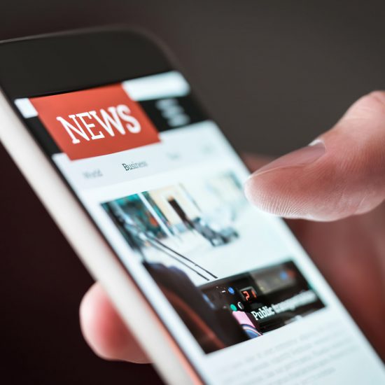 Mobile news application in smartphone. Man reading online news on website with cellphone. Person browsing latest articles on the internet. Light from phone screen.